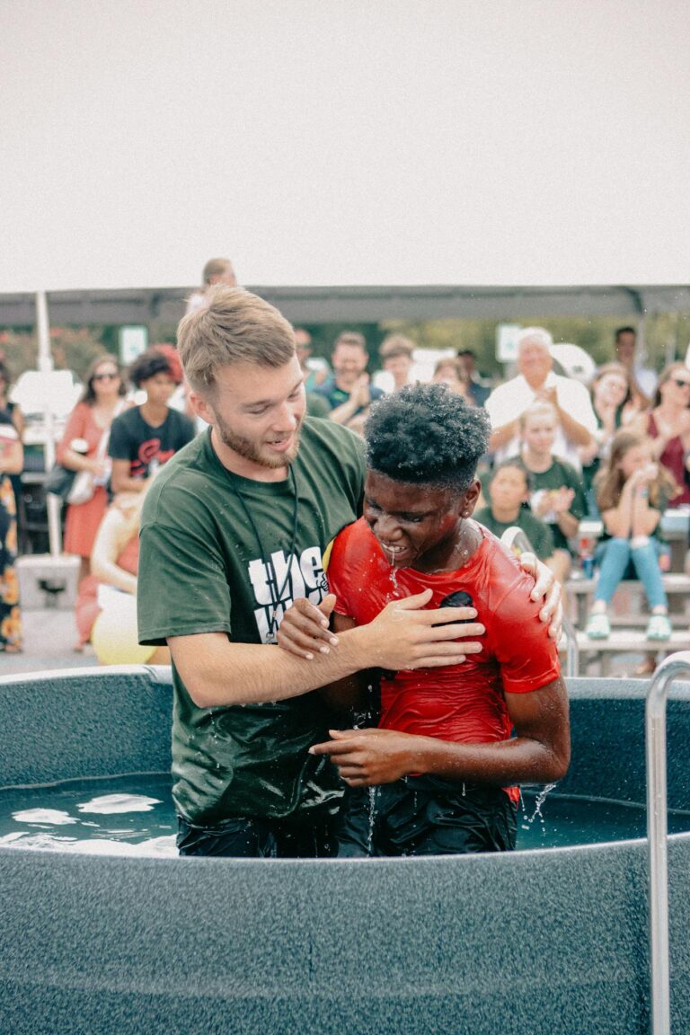A heartfelt baptism ceremony with two men in a vibrant church community setting in Clemson.