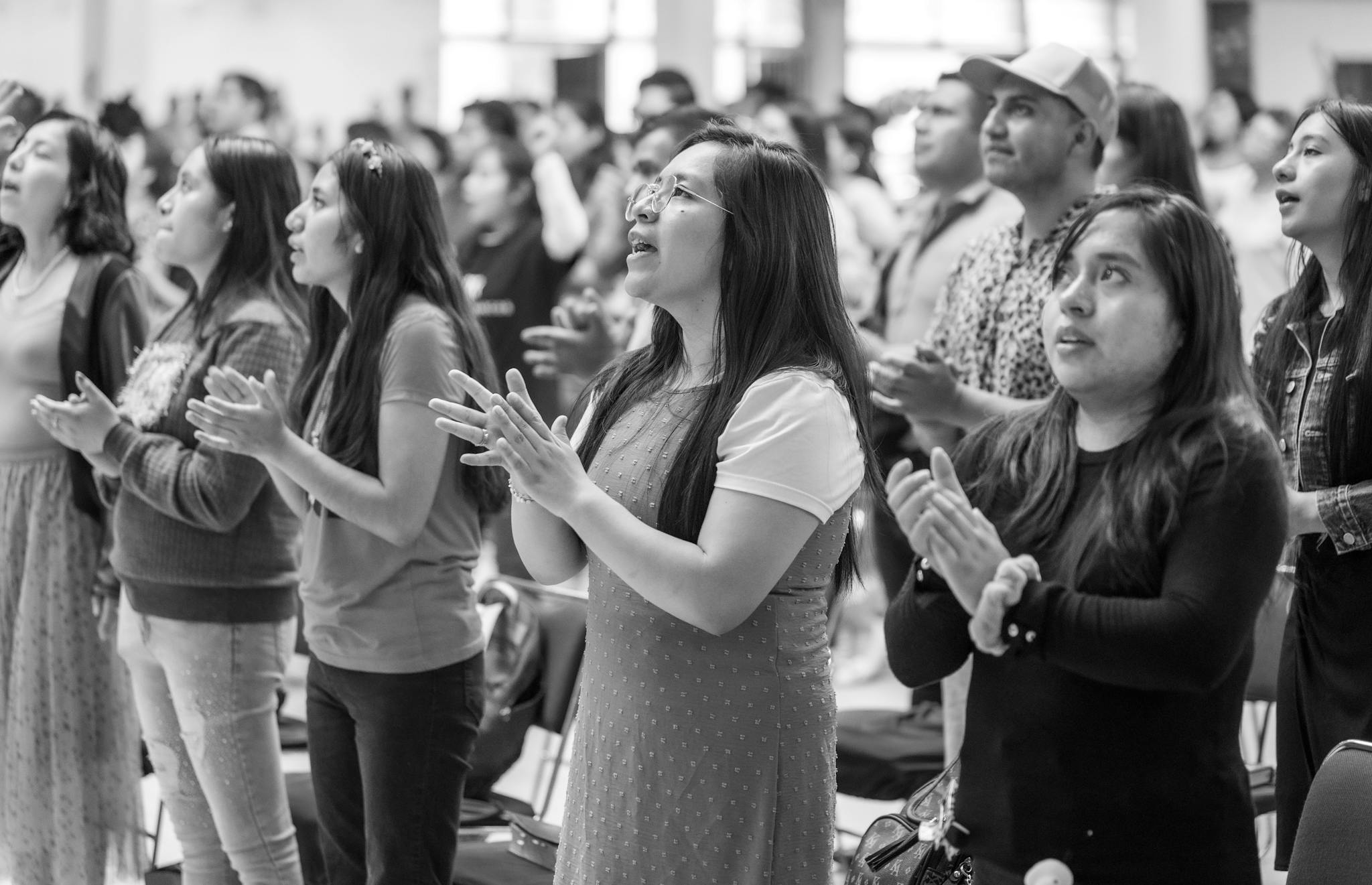 Women gathered together in Ciudad de México, praying and clapping in a religious setting.